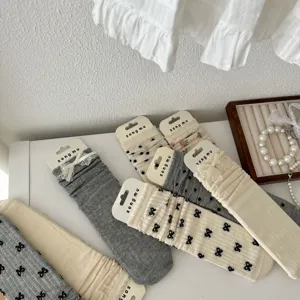 Detail shot of women's mesh ruffle mid tube slouch socks with cute bows and floral prints.