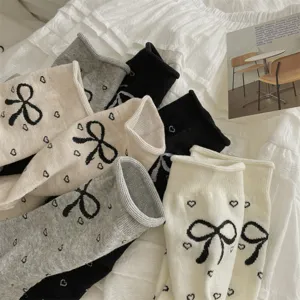 Detail view of women ballet socks featuring rolled cuffs, cute bow and heart jacquard design.