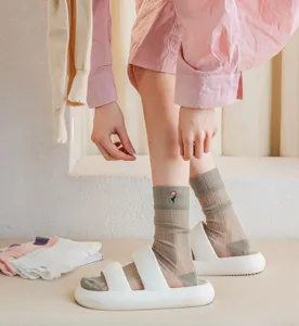 Detail view of women's sheer crystal silk mid-tube socks with delicate flower embroidery.