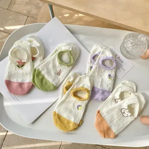 Detailopname van schattige geborduurde sneakersokken met kleurrijke contrastranden en ademende stof.