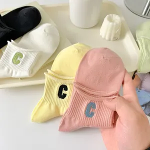 Close-up detail of cute women's ankle socks with embroidered letter C in vibrant colors.