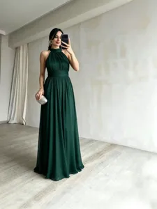 Elegante vestido de noche largo verde oscuro con cuello halter y faldón fluido y chic.