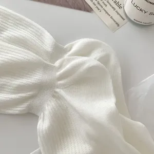 White knitted ribbed fabric detail with twist design, soft cotton texture for spring summer style.