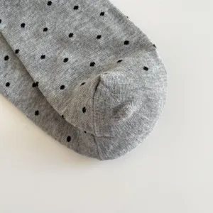 Detailed close-up view of a grey cotton knit sock featuring cute black polka dots texture.