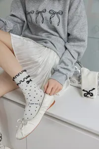 Detailed close-up shot of white polka dot ruffled mid-calf socks with cute bow styling.