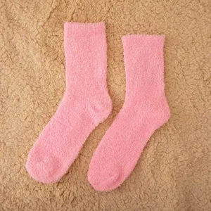 Pink fluffy coral fleece winter socks detail, soft cozy sleep floor socks close-up view.
