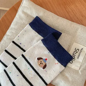 Close-up detail of knitted mid-tube socks featuring stripes, speckles and cute dog embroidery.