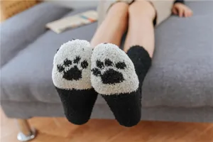 Primo piano di calzini invernali peluche con motivo di zampe per un comfort ottimale in casa.