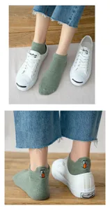 Nahaufnahme von Damen-Kurzsocken mit süßem Cartoon-Stick an der Ferse und weißen Freizeitschuhen.