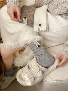 Close-up of thick knitted stackable socks with button label detail, cozy lifestyle footwear shot.