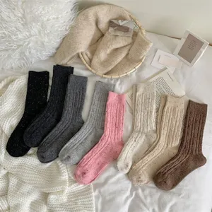 Detailed view of thick speckled cable knit slouch wool socks in cozy lifestyle flat lay.