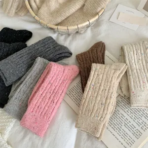 Close-up detail of thick cable knit wool socks in various colors with colorful speckles.