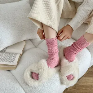 Detail shot of cozy thick cable knit slub yarn socks paired with fluffy plush indoor slippers.