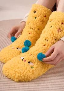 Detailed close-up of thick fluffy fleece floor socks with cute embroidery and blue pom-poms.
