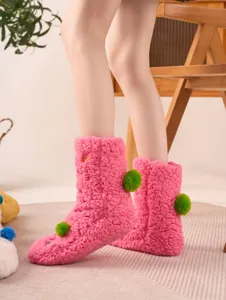 Close-up detail of cozy pink fuzzy floor socks featuring cute green pom-pom decorations.