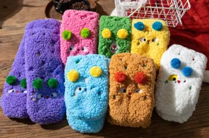 Detailed view of thick fuzzy sherpa fleece floor socks with cute cartoon embroidery and pom poms.