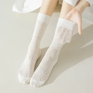 Close-up detail of white cotton hollow out mid-calf socks with cute knit heart pattern and rolled edge.