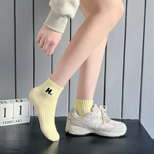 Close-up detail of women solid color short ankle socks with cute letter H embroidery.