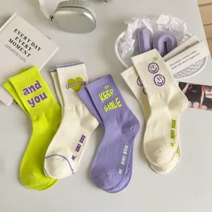 Detailed shot of cute aesthetic mid-calf socks with letter print and smiley face design.