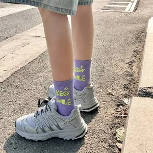 Purple mid tube socks featuring yellow Keep Smile letter print paired with grey sneakers.