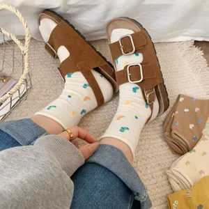 Close-up of Japanese style white patterned mid-tube socks paired with brown double buckle sandals.