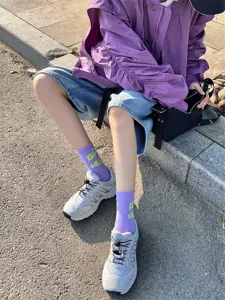 Women casual mid-tube socks featuring stylish English print paired with fashion sneakers outdoors.