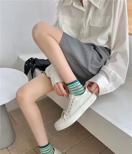 Detail view of women's short cotton socks with green stripes and cute embroidered letter.