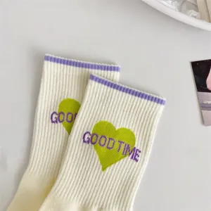 Close-up detail of women's knit mid-calf socks with purple cuffs and green heart text.