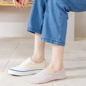 Close-up detail van schattige geborduurde roze enkelsokken gecombineerd met een witte sneaker.