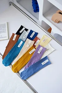 Detailed view of colorful stacked crew socks with rolled cuffs neatly arranged on a white table.