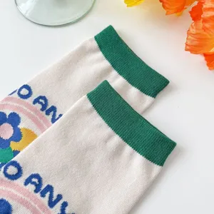 Close-up detail of women's floral mid-calf socks with green cuff and knit pattern design.