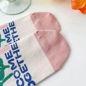 Detail shot of women's cute preppy style mid-calf socks featuring woven English text and pink toes.