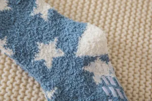 Detailed view of fluffy coral fleece fuzzy socks with star patterns and anti-slip grip sole.