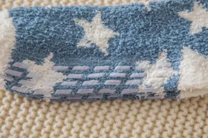 Close-up detail of fuzzy coral fleece winter anti-slip floor socks with cute white star pattern.