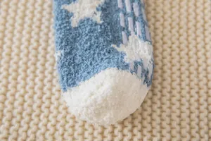 Cozy fuzzy non-slip floor sock detail, soft coral fleece texture with star pattern.