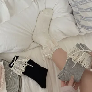 Vue détaillée de chaussettes mi-hautes en dentelle à volants doux avec nœuds délicats.