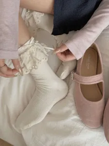 Vue detaillee de chaussettes mi-hautes blanches a volants de dentelle et joli ruban de style JK.