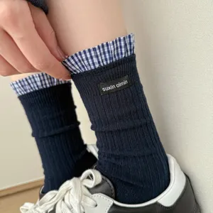 Close-up detail of dark blue ribbed socks with plaid ruffle trim and woven label design.