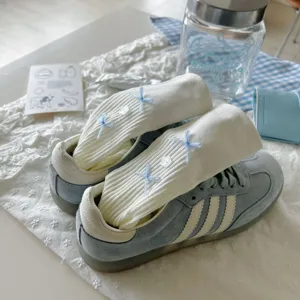 Detailed shot of white ribbed fashion socks with cute blue bows for sweet everyday style.