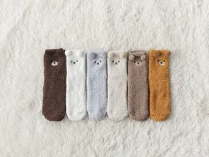Dettaglio di calzini soffici in pile corallo con simpatiche orecchie d'orso 3D colorate.