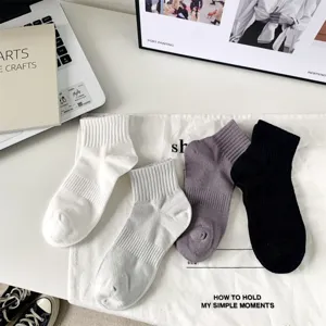 Close-up detail shot of four assorted colors casual cotton crew socks on white cloth.