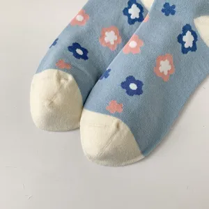 Close up view of cute floral pattern detail on light blue cotton socks with white heel and toe.