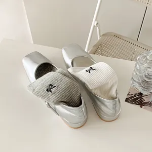 Metallic silver ballet flat shoes paired with cute bow embroidered socks, stylish footwear detail.
