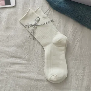 White ribbed mid-tube socks featuring a delicate silver ribbon bow detail, soft fabric.