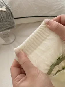 Gros plan sur les chaussettes en tricot doux avec un nœud vert et poignet côtelé.