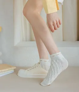 Detailed shot of women's white mesh short socks with delicate pattern worn with canvas shoes.