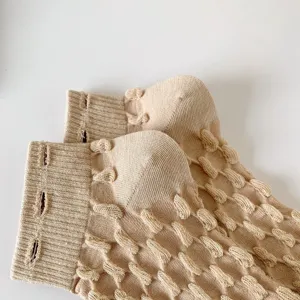 Close-up detail view of women's beige knit socks featuring unique 3D popcorn texture cuff.
