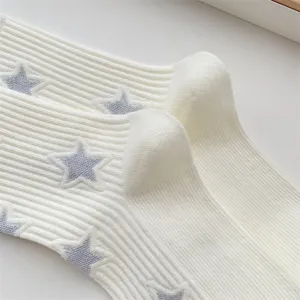 Close up detail view of white ribbed knit socks featuring cute grey star patterns and stretch fabric.