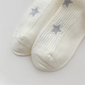 Close-up detail of white ribbed socks featuring embroidered silver stars, soft cotton blend.