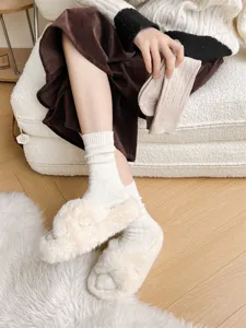 Cozy thick wool knit socks and plush fuzzy slippers for women, warm winter indoor wear.